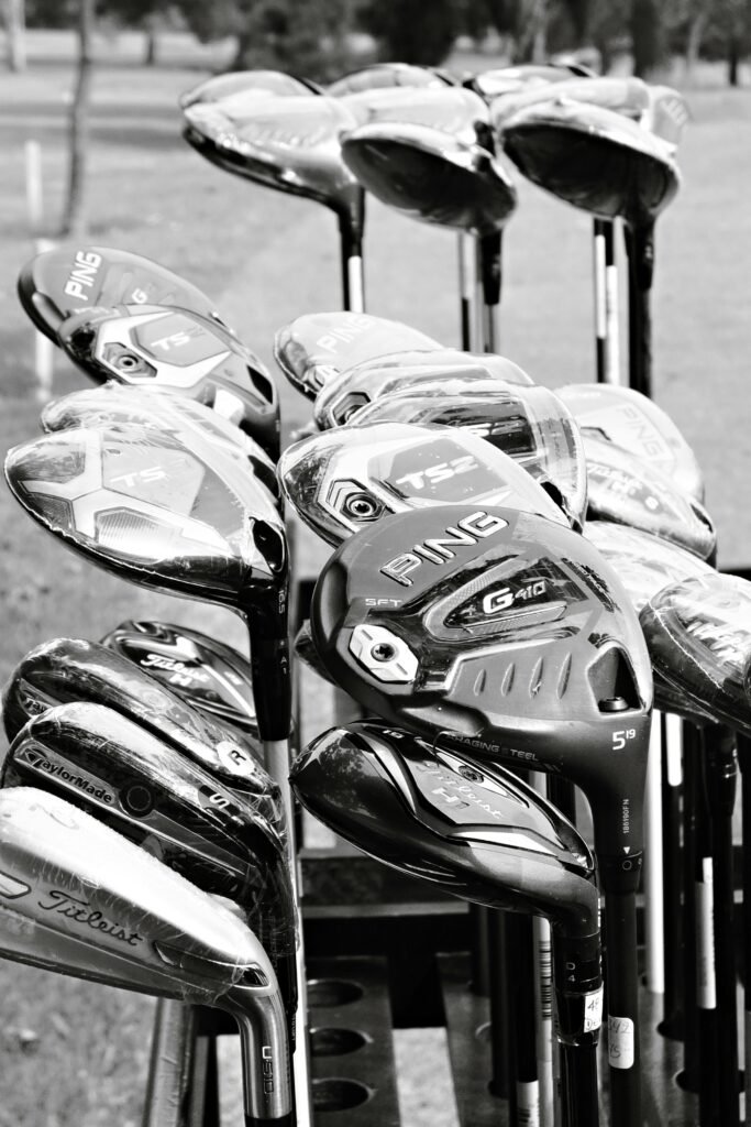 Artistic black and white shot of assorted golf clubs outdoors.